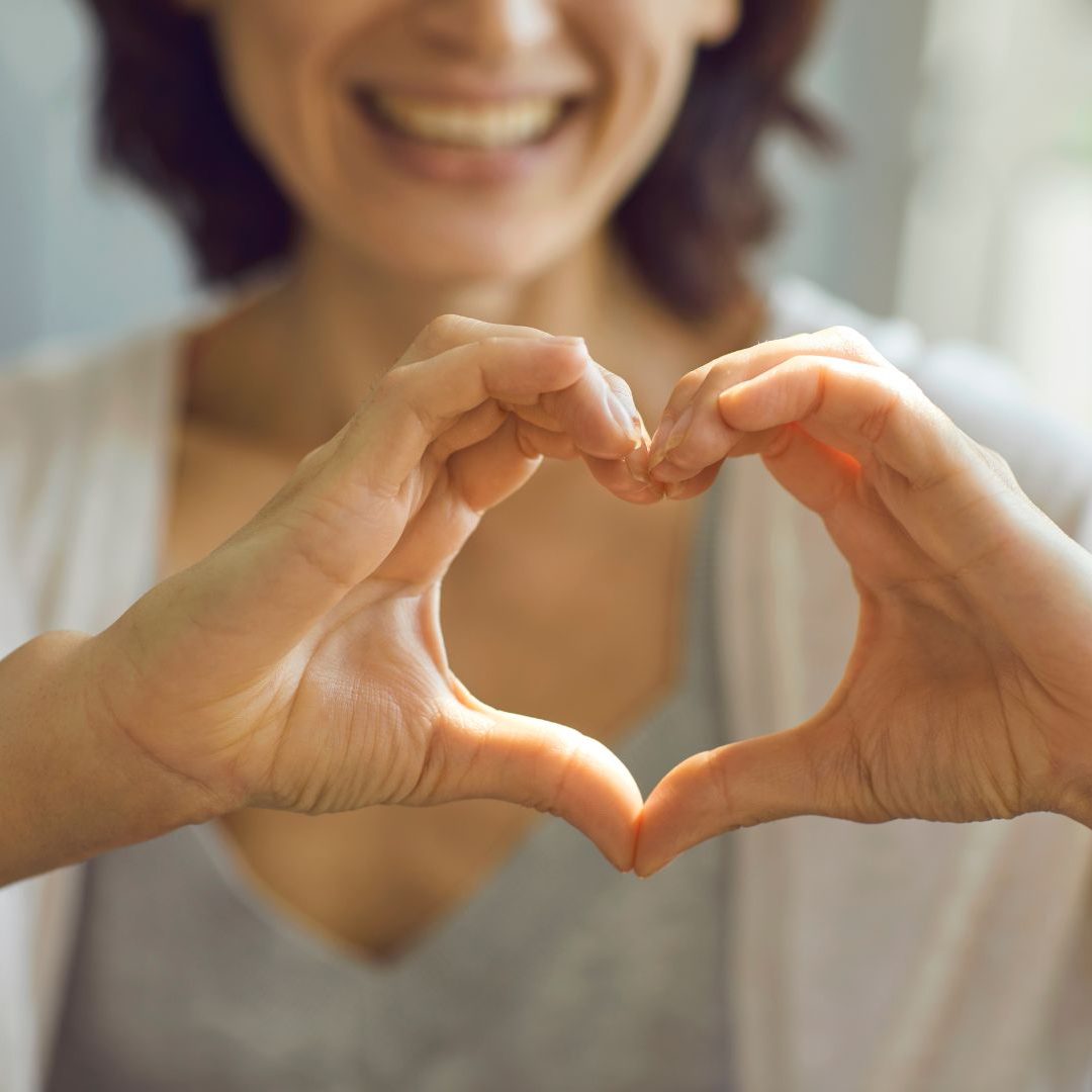 Una mujer está haciendo una forma de corazón con sus manos.