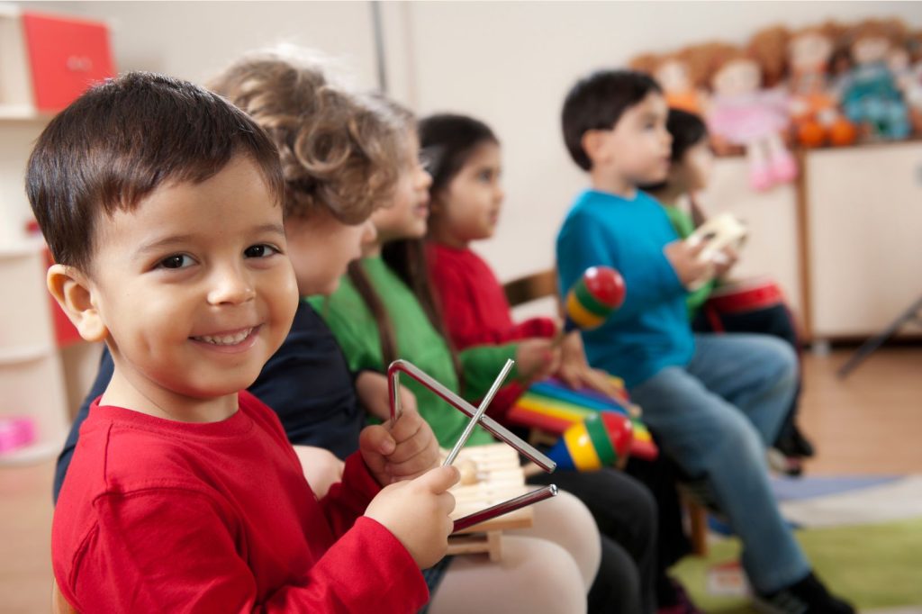 Un grupo de niños pequeños sentados en un salón de clases.