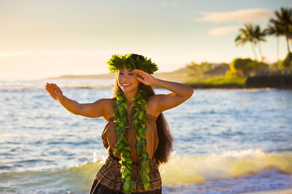 Una mujer hawaiana que lleva un lei en la playa.